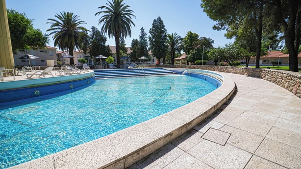 A swimming pool with a curved edge, surrounded by a stone wall and a tiled deck. - Intersur Independencia (Termas de Rio Hondo)