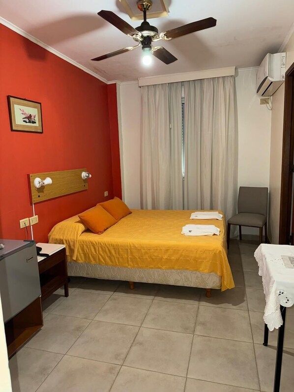 A hotel room with a bed, a desk, a chair, a ceiling fan, and an air conditioning unit. - Intersur Independencia (Termas de Rio Hondo)