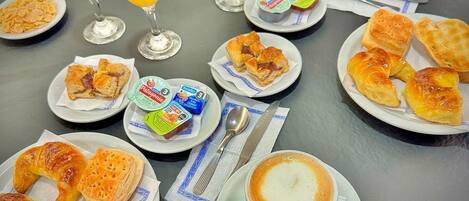 A table set with various breakfast items including pastries, juices, and a cup of coffee.