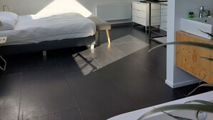 Una camera da letto moderna con finestra a soffitto, un letto, una TV e un bagno con specchio e lavabo.