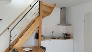 Una cucina funzionale con una scala in legno, un tavolo da pranzo con sedie e una lampada moderna.