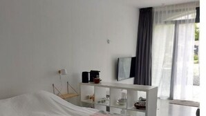 Ett modernt sovrum med en stor säng, ett nattduksbord, ett litet skrivbord och ett fönster med gardiner.