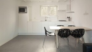 Une cuisine moderne avec des meubles blancs, un four à micro-ondes, un évier et une fenêtre. On y trouve une table à manger avec quatre chaises.