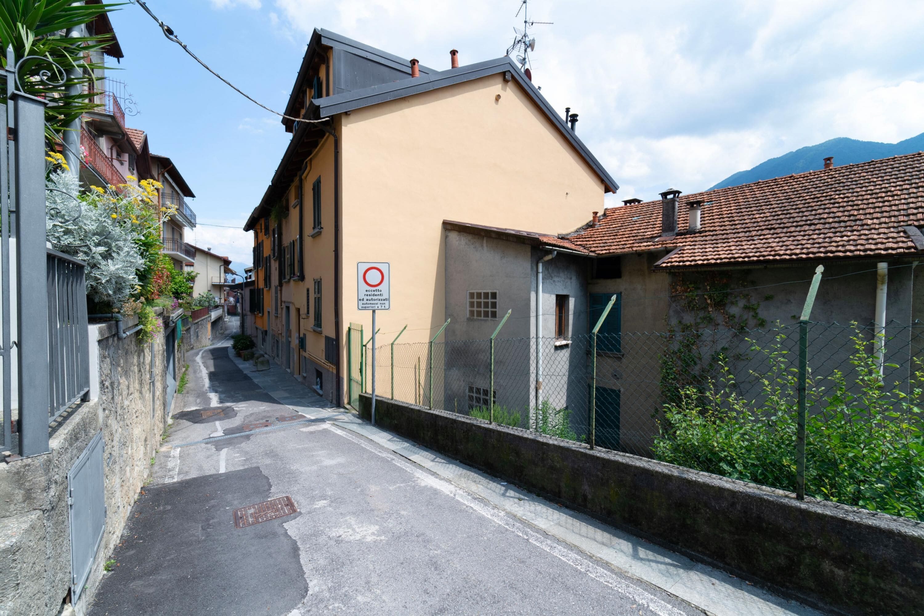 A narrow street with buildings on either side, a no parking sign, and a clear sky.
