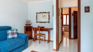 A living room with a blue sofa, wooden dining table, and a framed picture on the wall. - Greenway Apartment by Wonderful Italy (Colonno)