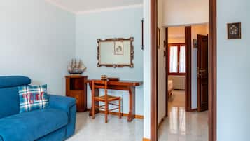 Una sala de estar con sofá azul, mesa de comedor de madera y un cuadro en la pared.