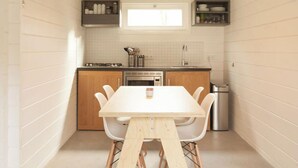 A compact kitchen with white cabinets, a wooden countertop, and a white table with chairs. - Cottage 2 & Cottage 3 (Koudekerke)