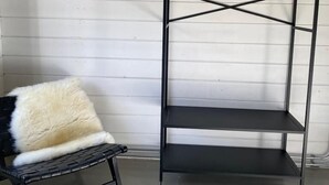 A black metal shelf unit with three shelves and a hanging rack against a white paneled wall. - Cottage 2 & Cottage 3 (Koudekerke)