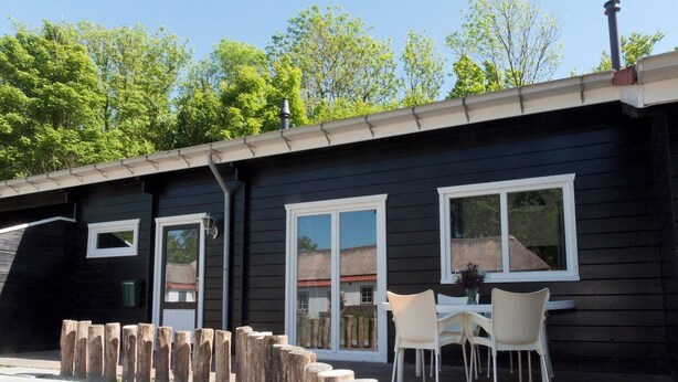 A building with a dark exterior, white-framed windows, and a wooden fence. - Cottage 2 & Cottage 3 (Koudekerke)