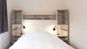 A bedroom with a bed, two bedside tables with lamps, and built-in shelving units. - Cottage 2 & Cottage 3 (Koudekerke)