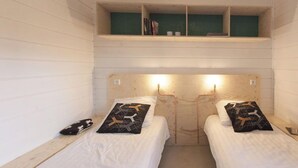 A small, cozy room with two single beds, each with a pillow and a small shelf above. - Cottage 2 & Cottage 3 (Koudekerke)
