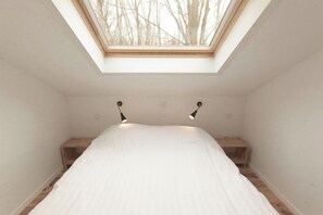 A bedroom with a skylight, a bed, and two bedside tables.