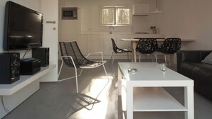 Un salon moderne avec un téléviseur à écran plat, une table basse blanche et des chaises noires.