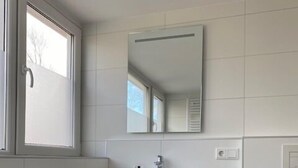 Un baño moderno con una bañera independiente, un tocador de madera con lavamanos y un inodoro.