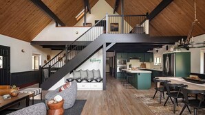 Un loft spazioso con soffitto alto, una scala, una cucina e un'area pranzo.
