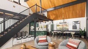 Un ambiente moderno con scala, zona salotto, spazio pranzo e cucina.