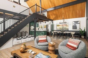 A modern interior with a staircase, seating area, dining space, and kitchen.