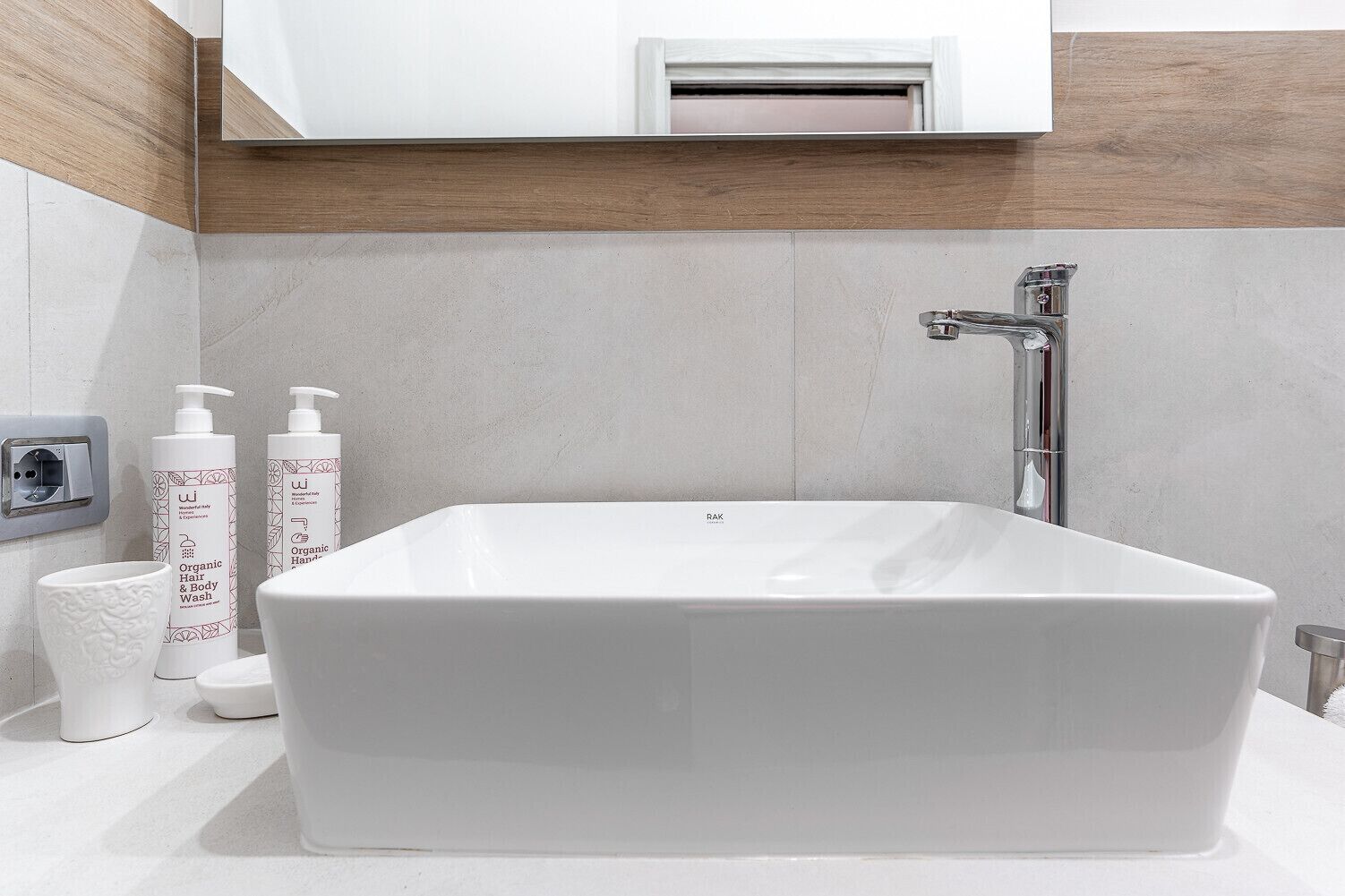 A modern bathroom with a rectangular bathtub, a white toilet, and two bottles of organic hair and body wash.