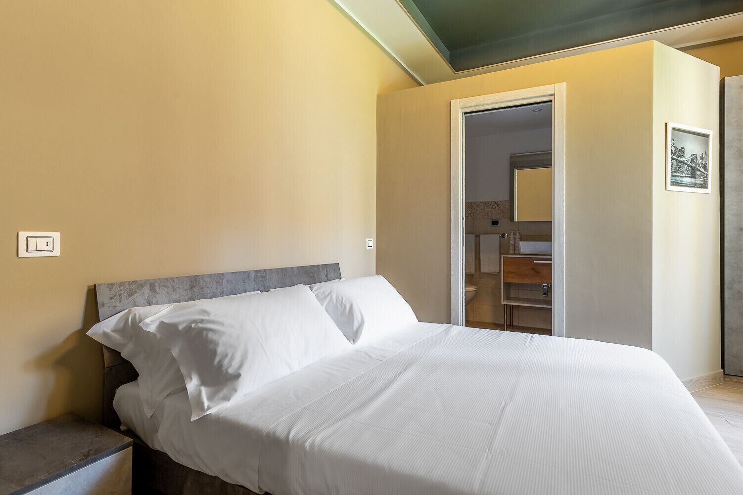 Un dormitorio con cama, mesita de noche y puerta que da al baño.