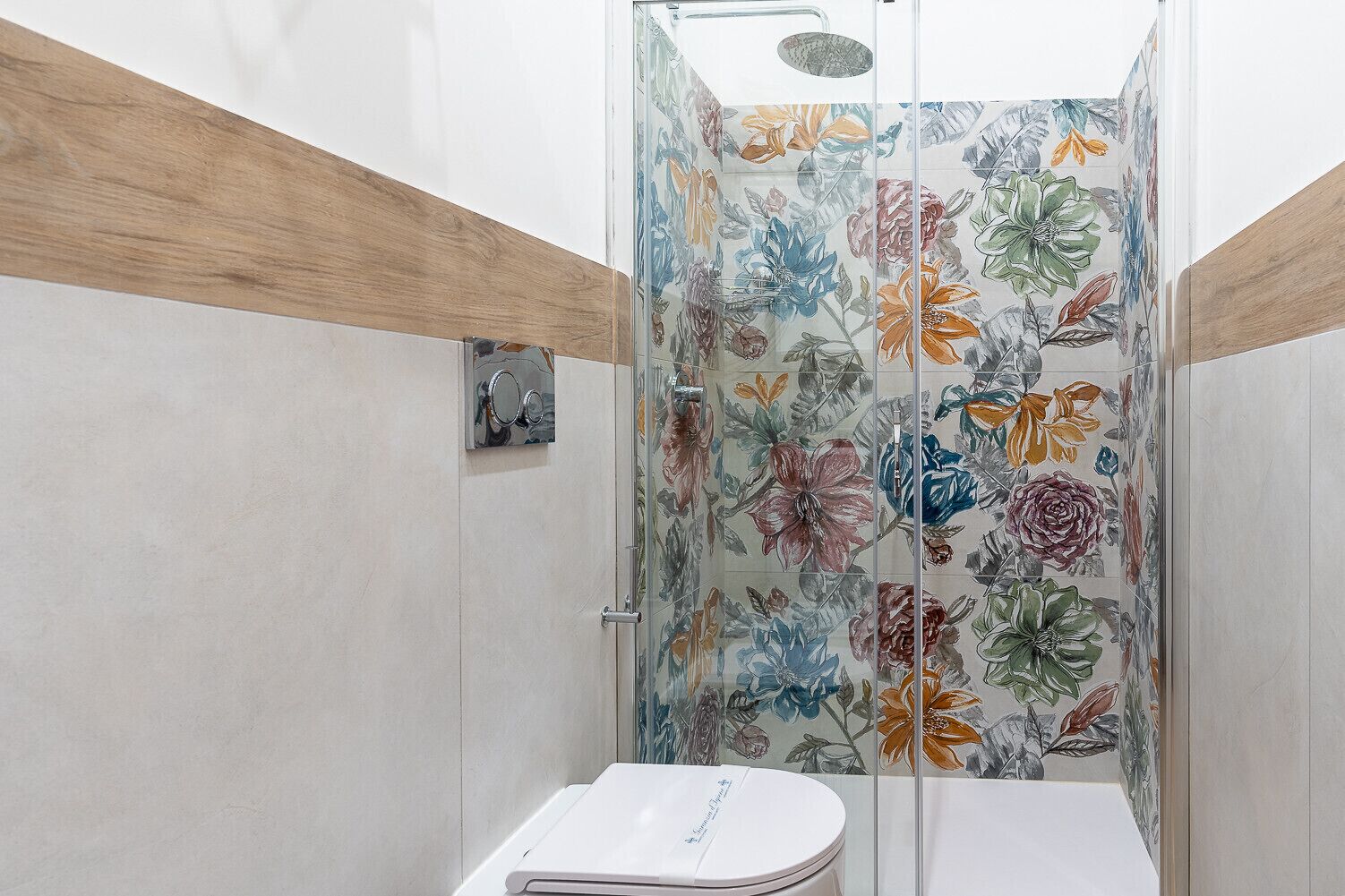A shower with a glass door featuring a floral pattern.