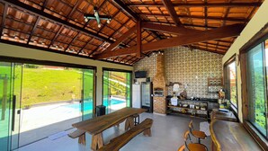 A spacious kitchen with a large island, a built-in grill, and a view of a swimming pool.