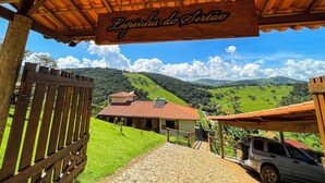 A wooden sign reading "La Sertão" above a rustic entrance with a paved path leading to a building with a red roof.