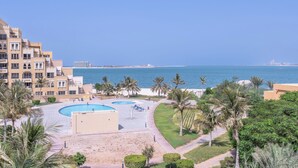 Un resort con piscina, palmeras y vista al mar.