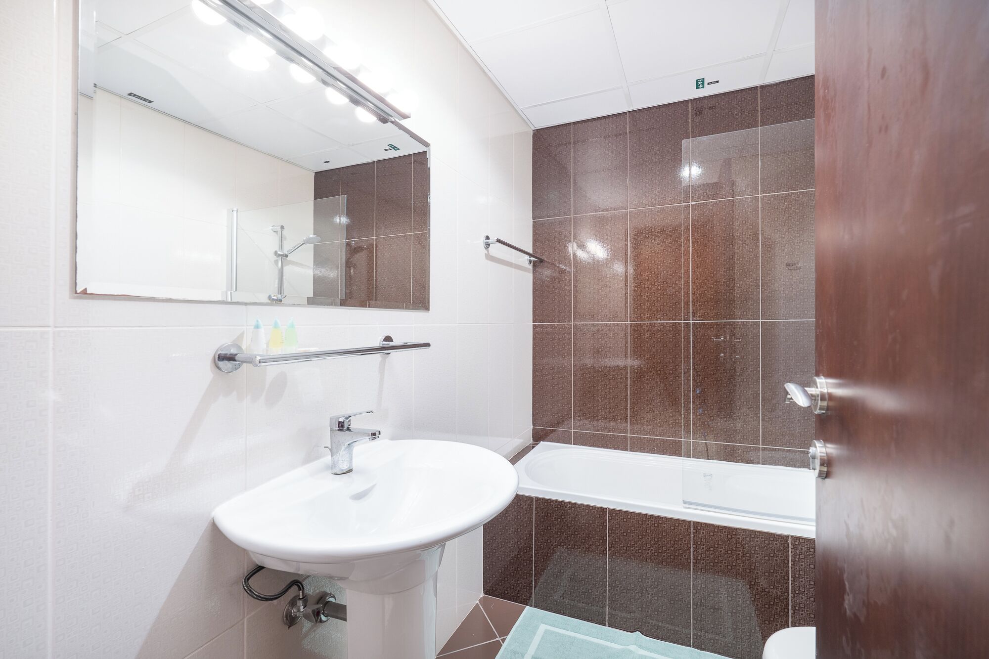 Un bagno moderno con un lavandino bianco, uno specchio, una doccia e una vasca da bagno.