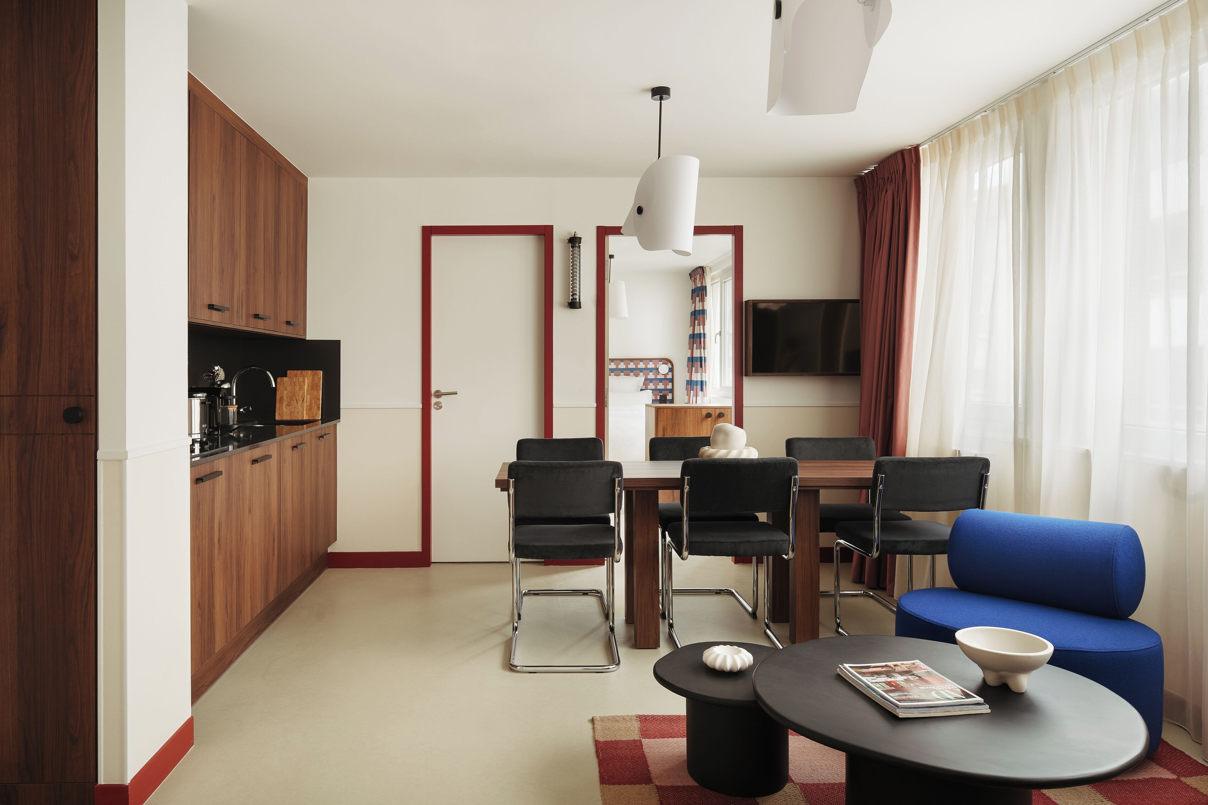 Un salon moderne comprenant un coin repas, des meubles en bois, un canapé bleu et un téléviseur à écran plat.