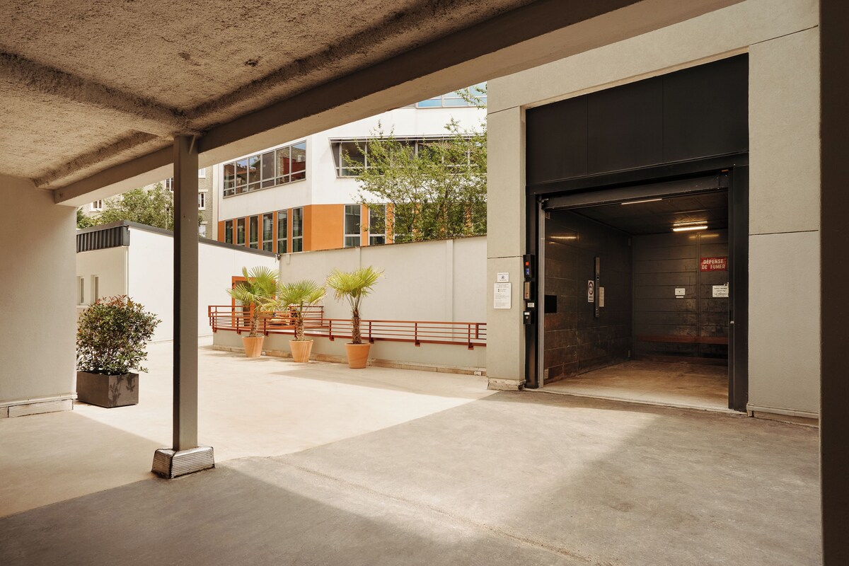 A building entrance with a covered area, potted plants, and a visible elevator door.