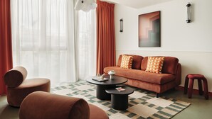 Een moderne woonkamer met een bank, poefjes, een salontafel en een vloerkleed.