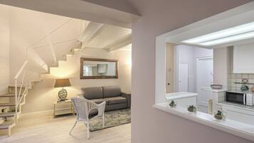 Un interior moderno con una escalera, un sofá, una silla y una zona de cocina.