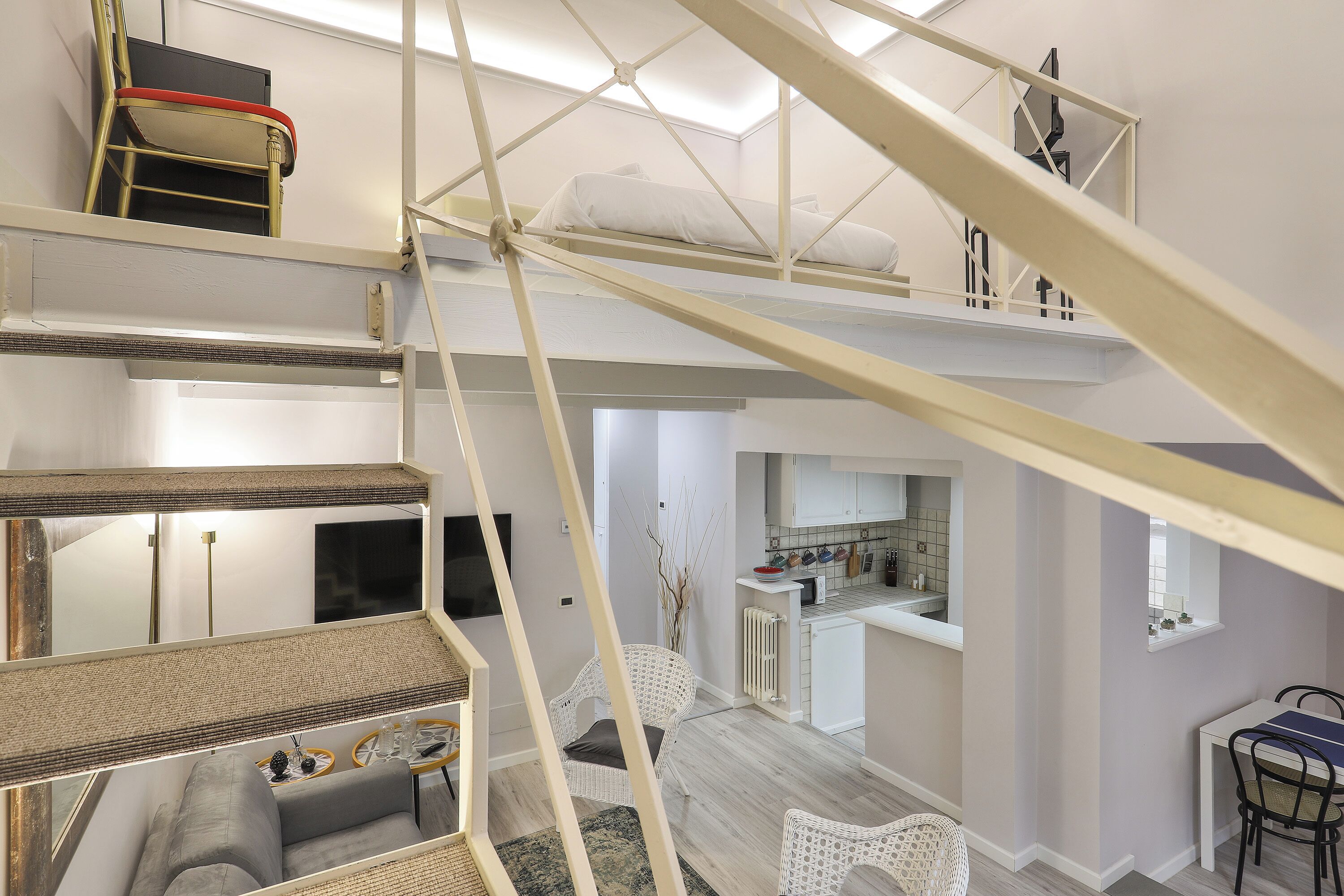 A multi-level interior with a staircase, a living area with a sofa, a dining table, and a kitchen area.