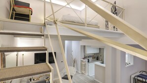 A multi-level interior with a staircase, a living area with a sofa, a dining table, and a kitchen area. - Giglio Bianco (Florence)