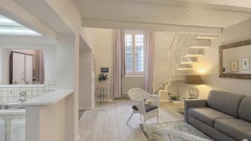 Una sala moderna con una escalera, un sofá y un comedor con una cocina al fondo.