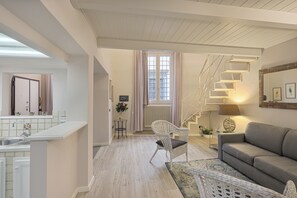 A modern living room with a staircase, a sofa, and a dining area with a kitchen in the background. - Giglio Bianco (Florence)
