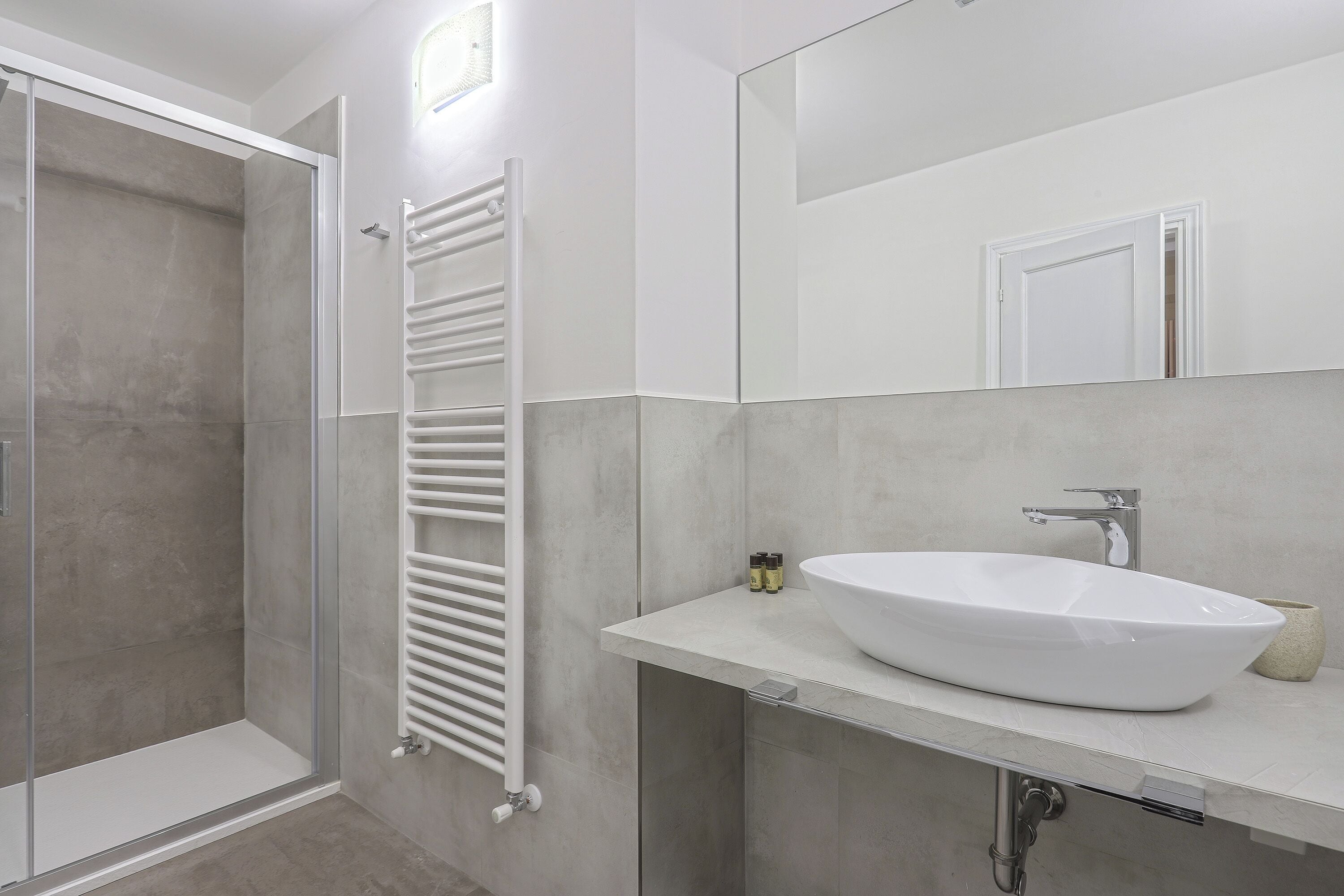 A modern bathroom with a glass shower enclosure, a white sink, and a large mirror.