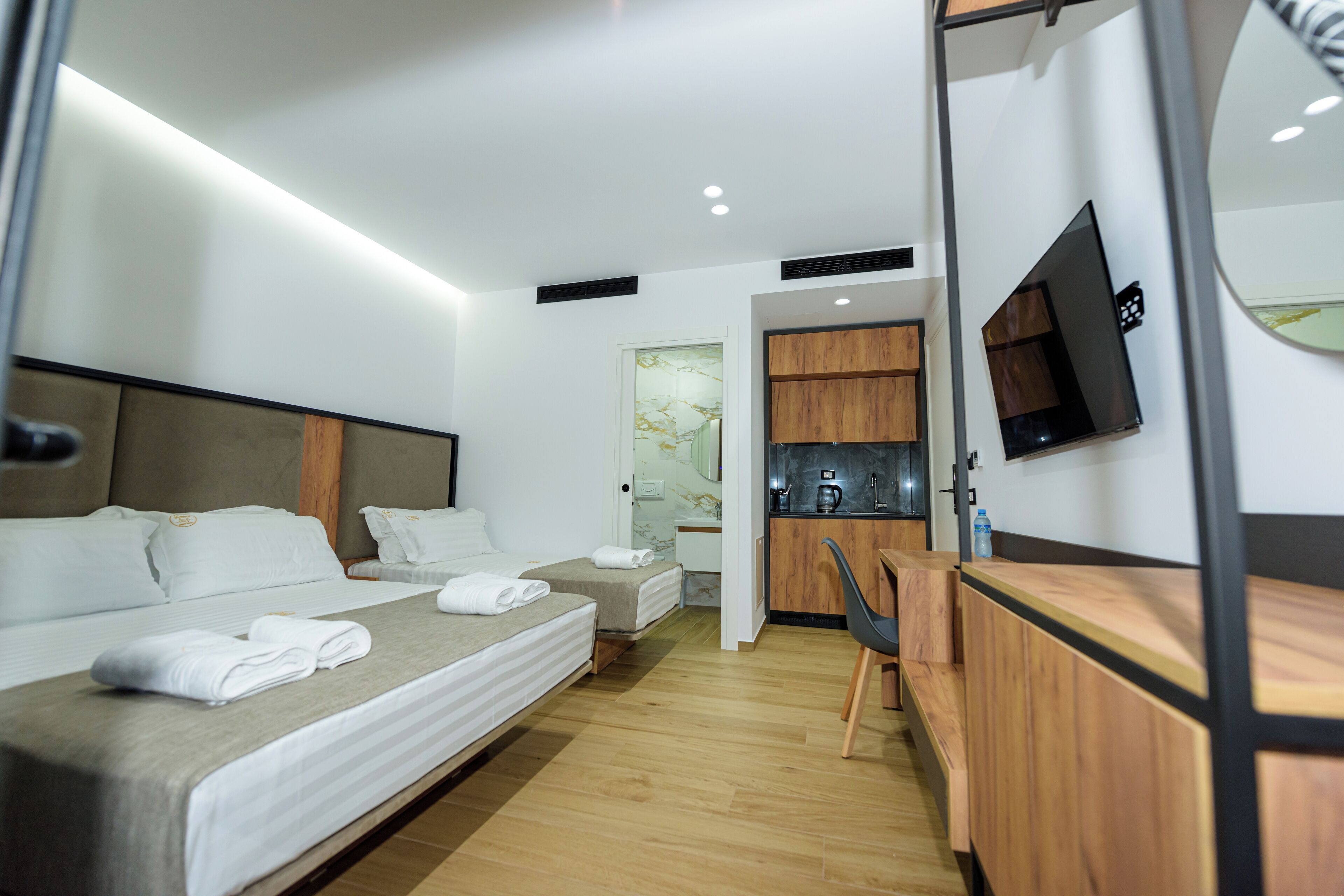 Quarto de hotel moderno com cama grande, escrivaninha e televisão.
