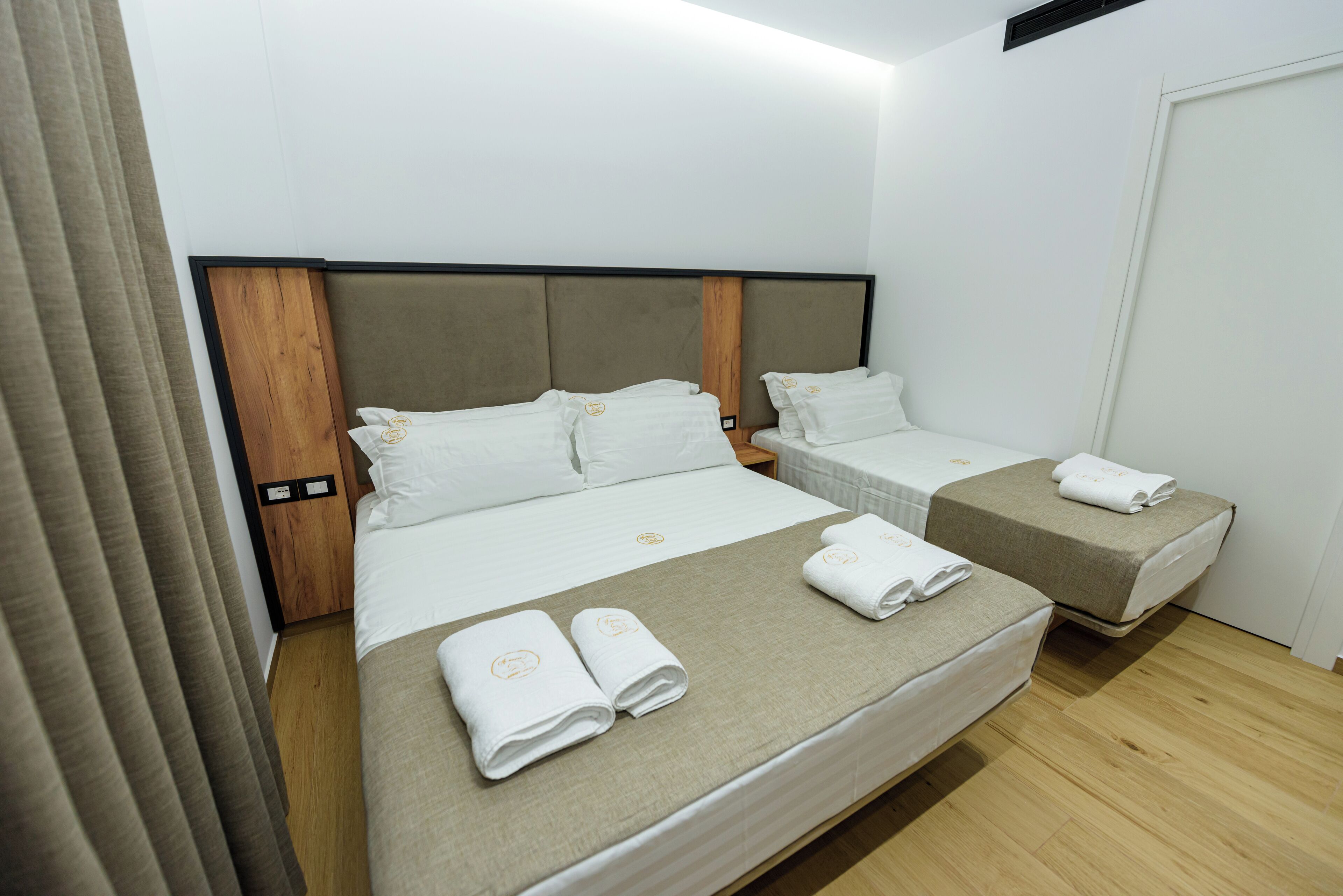 Ein Hotelzimmer mit einem großen Bett, zwei kleineren Betten und einem Holzkopfstück.