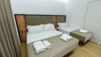 Ein Hotelzimmer mit einem großen Bett, zwei kleineren Betten und einem Holzkopfstück.