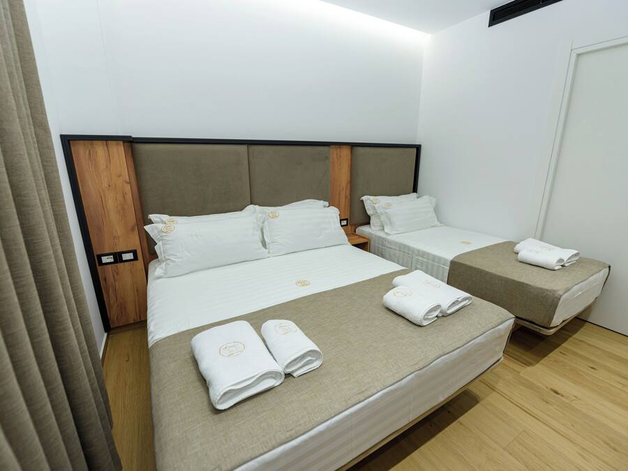 Une chambre d’hôtel avec un grand lit, deux petits lits et une tête de lit en bois.