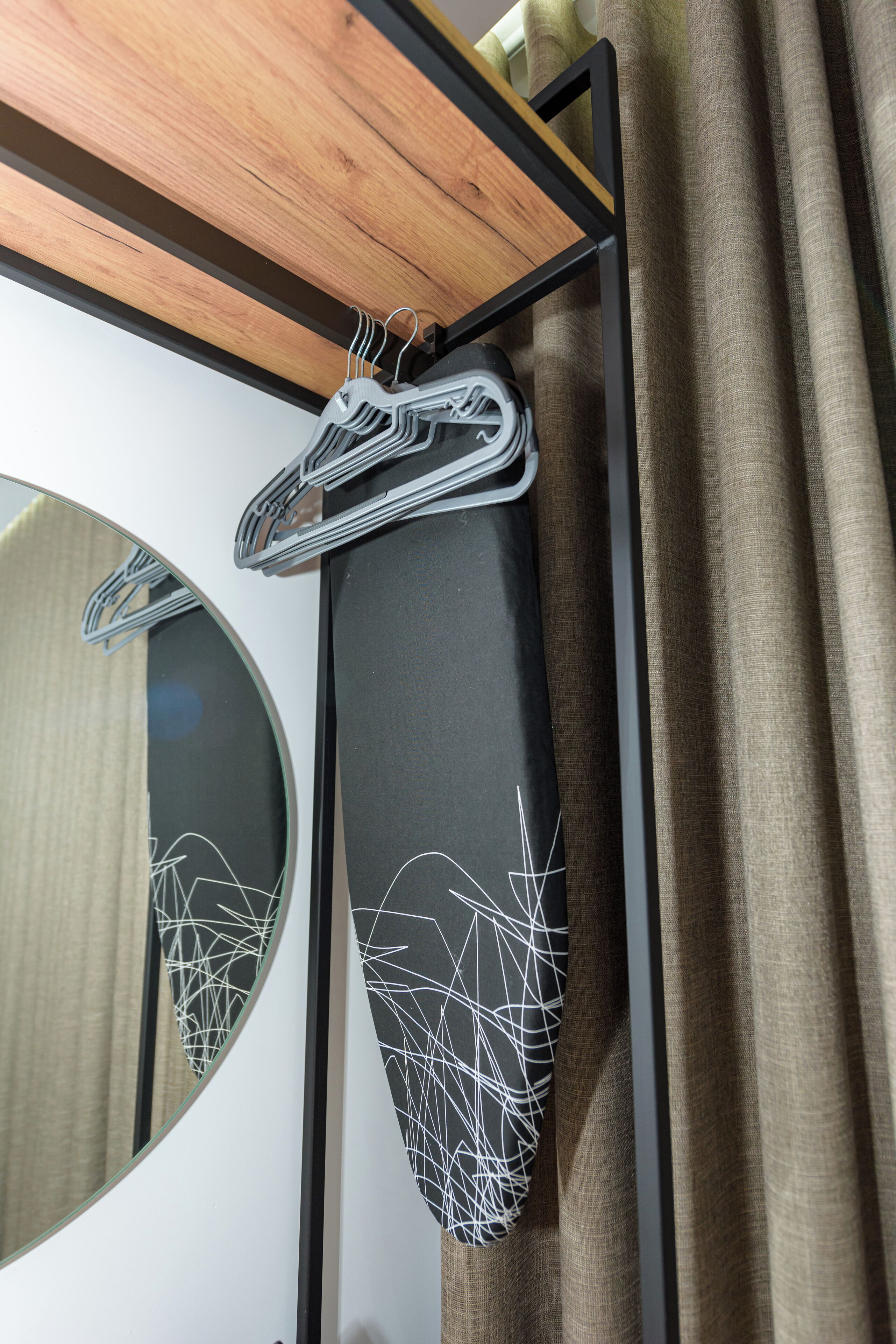 A mirror with a circular frame, a black hanging garment, and a wooden ceiling.