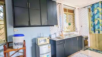 A compact kitchen with dark cabinets, a microwave, a small refrigerator, and a water dispenser.
