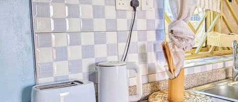 A kitchen with a toaster, a kettle, and a woven placemat on the counter.