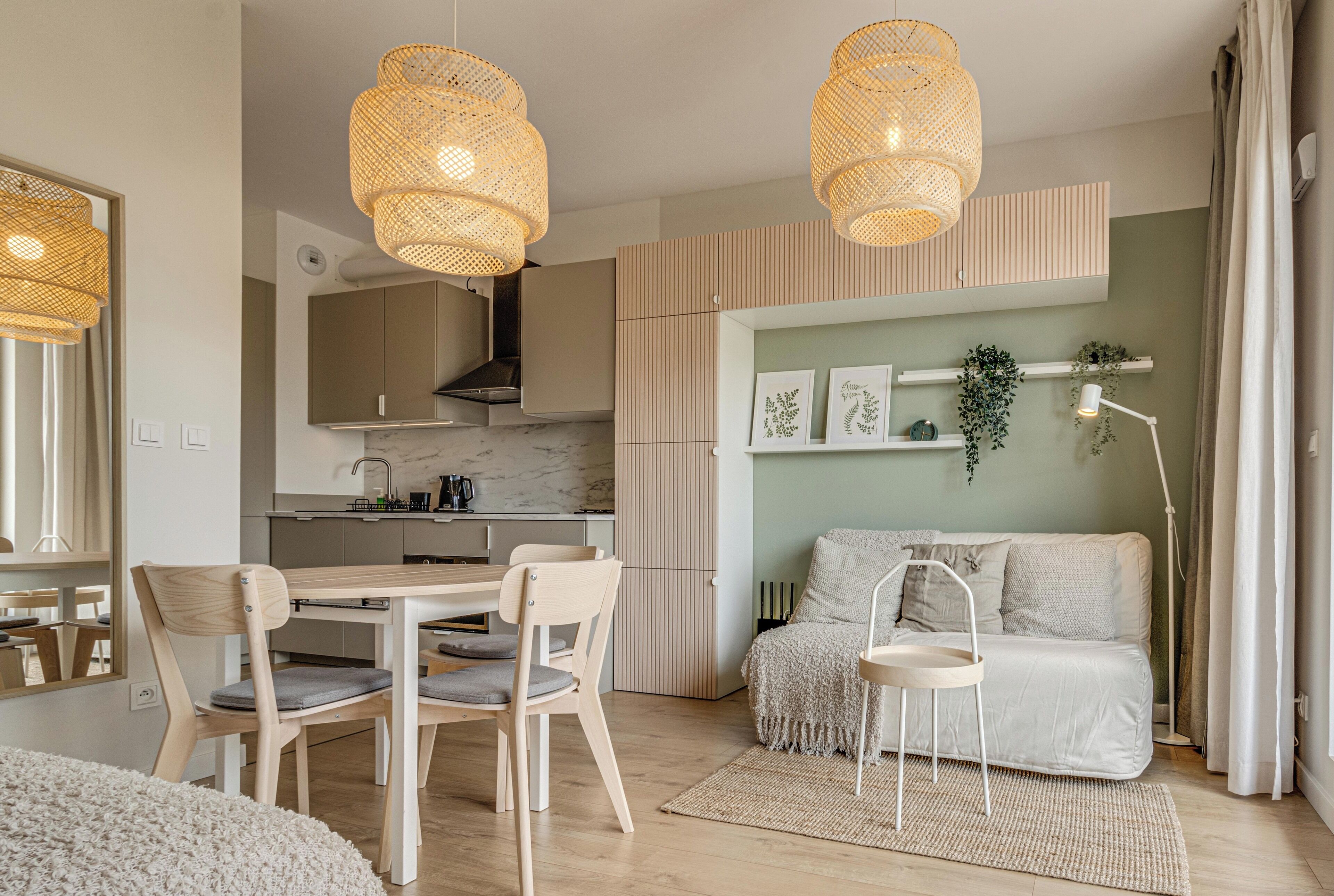 Ein modernes Wohnzimmer mit Sofa, Esstisch, Stühlen und einer Küchenzeile im Hintergrund.