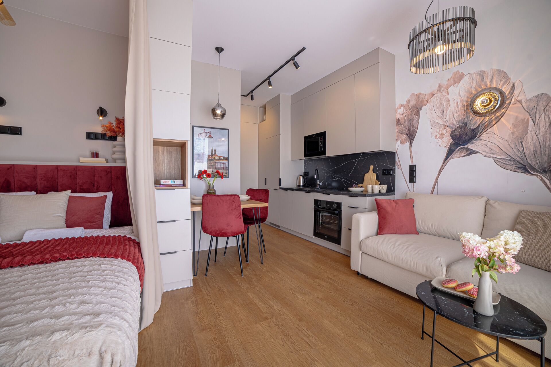 Moderni hotellihuone, jossa on sänky, sohva, ruokailutila ja keittiö.