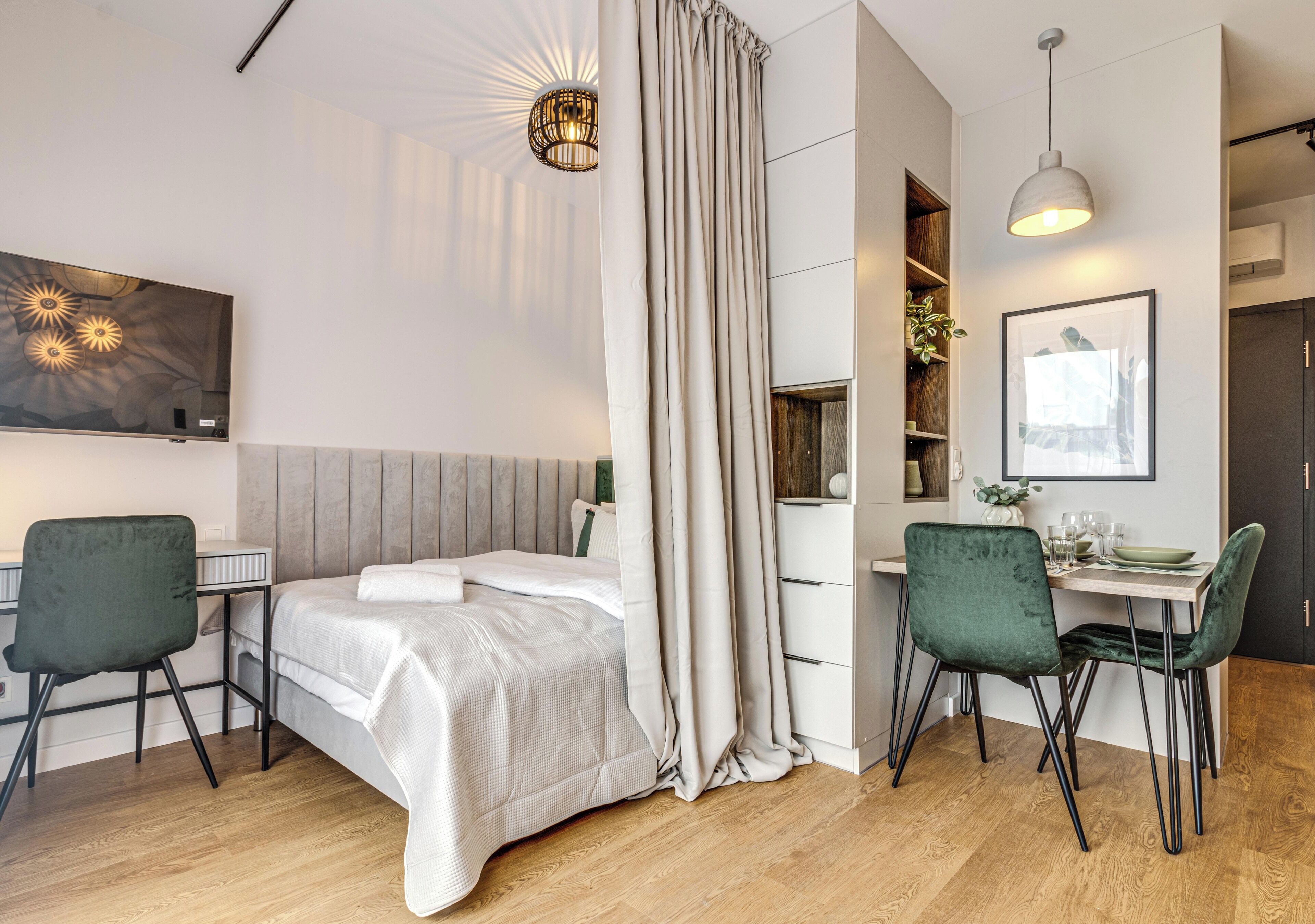 Une chambre d’hôtel moderne, équipée d’un lit, d’un bureau, de deux chaises, d’une table à manger et d’une grande fenêtre avec des rideaux.