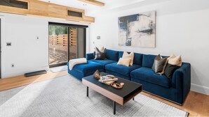 Ein modernes Wohnzimmer mit einem blauen Sofa, einem Couchtisch und einem großen, abstrakten Gemälde an der Wand.