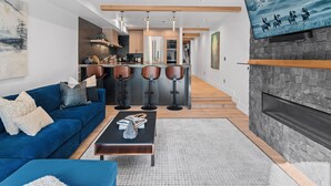 Een moderne woonkamer met een blauwe bank, een salontafel en een open haard.