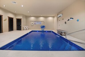 An indoor swimming pool with a clear water surface, a diving board, and a lifeguard sign. - Panoramic Paradise Splash – A Splash of Fun All Around (SEVIERVILLE)